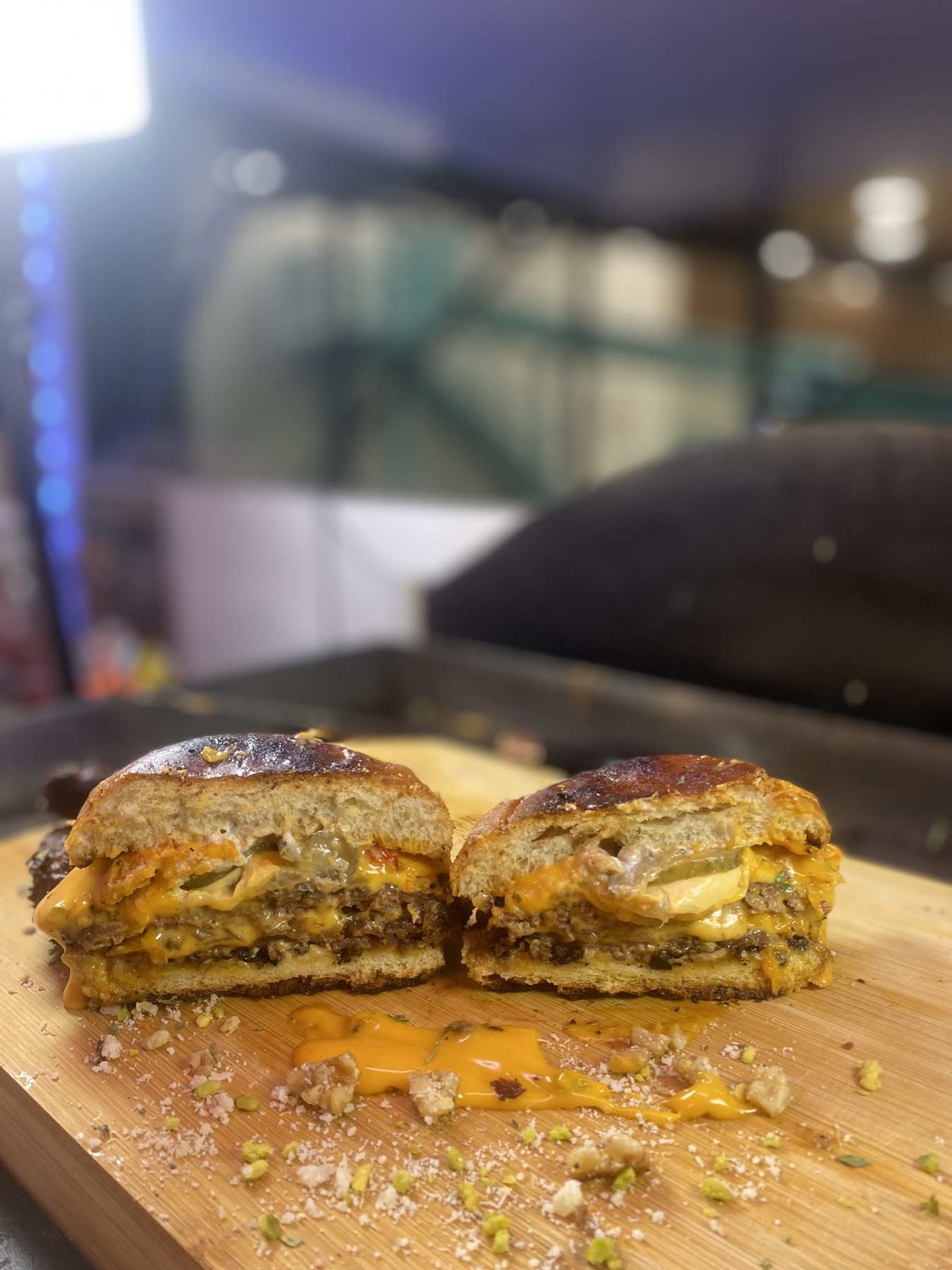 Aufgeschnittener Burger mit zwei Patties und fließendem Käse auf einem Holzbrett